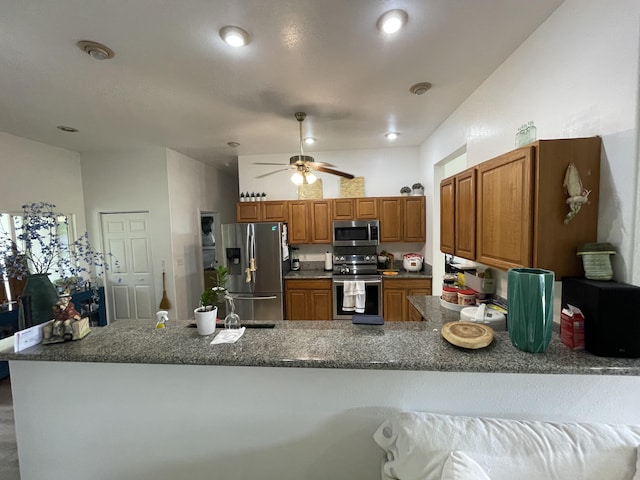 15-1765 28th Ave, Keaau, HI 96749 - kitchen featuring appliances with stainless steel finishes, a peninsula, brown cabinetry, ceiling fan, and dark stone countertops