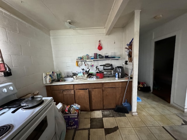 27-292 Old Mamalahoa Hwy, Papaikou, HI 96781 - kitchen featuring white range with electric cooktop, light countertops, concrete block wall, brown cabinetry, and light flooring