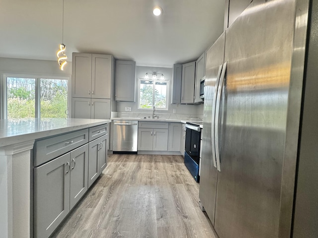 16-2142 Kuhio Dr, Pahoa, HI 96778 - kitchen with gray cabinetry, stainless steel appliances, light wood-type flooring, decorative light fixtures, and light stone countertops