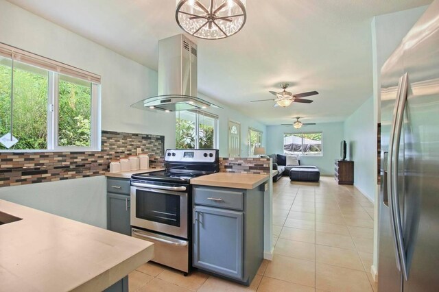 14-3556 Seadrift Rd, Pahoa, HI 96778 - kitchen featuring appliances with stainless steel finishes, island range hood, gray cabinets, decorative backsplash, and light tile patterned floors