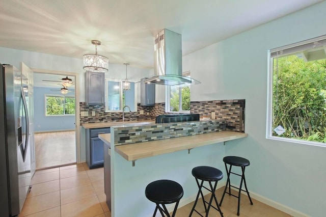 14-3556 Seadrift Rd, Pahoa, HI 96778 - kitchen with stainless steel fridge with ice dispenser, a breakfast bar area, a peninsula, island range hood, and backsplash