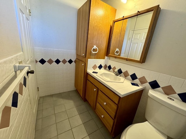74-5075 Kau Pl, Kailua-Kona, HI 96740 - bathroom with tile walls, a wainscoted wall, vanity, toilet, and tile patterned floors