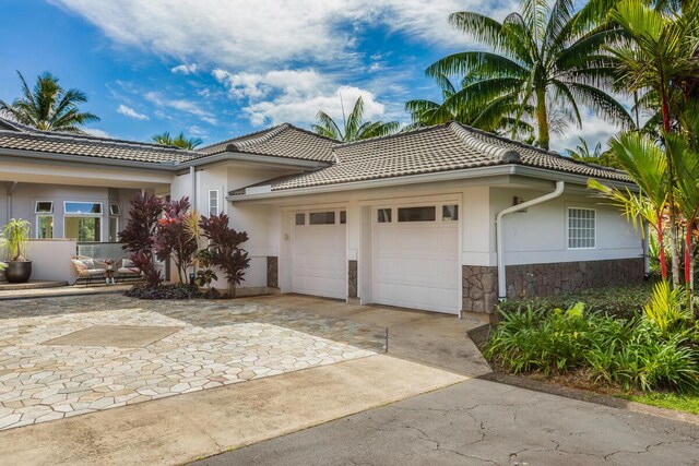 4100 Queen Emmas Dr Unit 7, Princeville, HI 96722 - view of property exterior featuring an attached garage, stone siding, driveway, and a tile roof