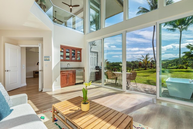 4100 Queen Emmas Dr Unit 7, Princeville, HI 96722 - living room featuring light wood-type flooring, wet bar, baseboards, and a towering ceiling