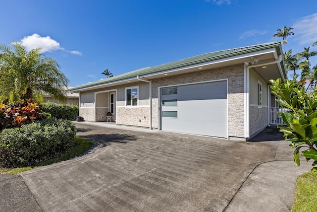 99 Kamalii St, Hilo, HI 96720 - view of front of house featuring concrete driveway, stone siding, and a garage