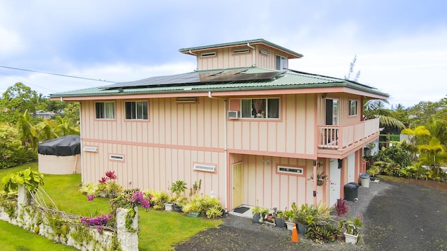 12-7059 Puulena St, Pahoa, HI 96778 - view of front of house featuring board and batten siding, solar panels, metal roof, and a front lawn