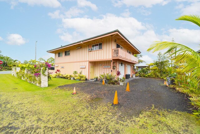 12-7059 Puulena St, Pahoa, HI 96778 - view of side of property featuring board and batten siding, a balcony, a lawn, driveway, and a garage