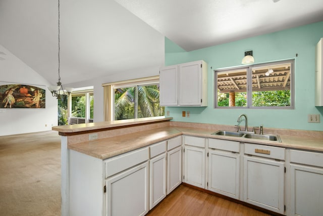4833 Ou Pl, Princeville, HI 96722 - kitchen featuring a sink, vaulted ceiling, a peninsula, white cabinetry, and a chandelier