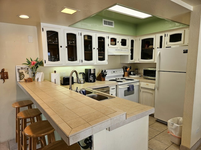 75-6082 Alii Dr Unit A201, Kailua-Kona, HI 96740 - kitchen featuring white appliances, under cabinet range hood, a peninsula, a sink, and a breakfast bar area