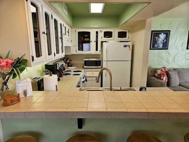 75-6082 Alii Dr Unit A201, Kailua-Kona, HI 96740 - kitchen featuring white appliances, under cabinet range hood, a sink, glass insert cabinets, and tile countertops