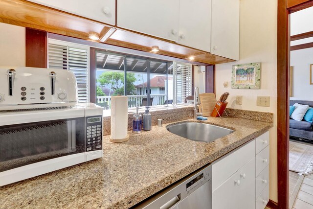 2253 Poipu Rd Unit 138, Koloa, HI 96756 - kitchen featuring a sink, white cabinets, white microwave, stainless steel dishwasher, and light stone countertops