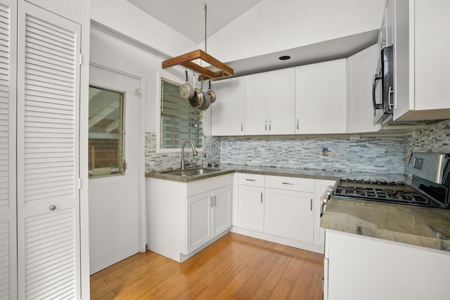5060 Nonou Rd, Kapaa, HI 96746 - kitchen with stainless steel range with gas cooktop, tasteful backsplash, light wood-style flooring, a sink, and white cabinets