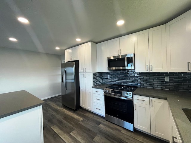 927 Puku St, Hilo, HI 96720 - kitchen with stainless steel appliances, backsplash, dark wood finished floors, dark countertops, and white cabinets