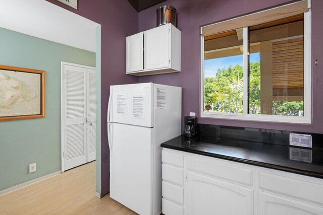 78-6800 Alii Dr Unit 6301, Kailua-Kona, HI 96740 - kitchen featuring freestanding refrigerator, dark countertops, light wood-type flooring, white cabinetry, and baseboards