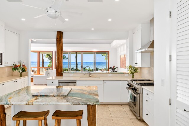 69-1708 Puako Beach Dr, Kamuela, HI 96743 - kitchen featuring appliances with stainless steel finishes, wall chimney range hood, a breakfast bar area, tasteful backsplash, and ceiling fan
