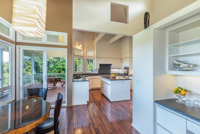 4633 Waiakalua St, Kilauea, HI 96754 - kitchen with a high ceiling, dark countertops, dark wood-style floors, white cabinets, and stainless steel oven