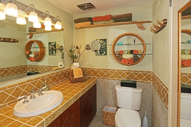 75-6016 Alii Dr Unit 211, Kailua-Kona, HI 96740 - half bath featuring toilet, vanity, a wainscoted wall, tile walls, and tile patterned flooring