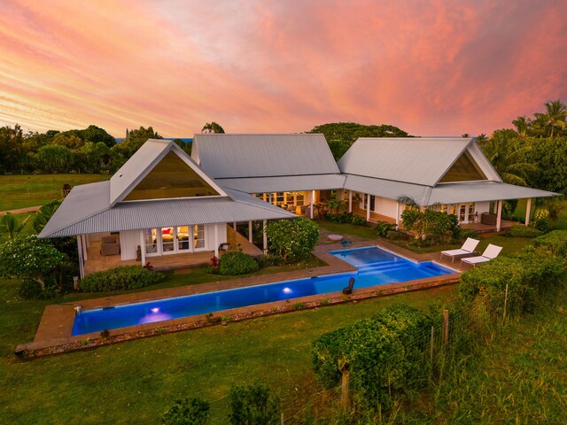 7465-C Koolau Rd, Kilauea, HI 96754 - pool at dusk featuring an outdoor pool, a yard, french doors, and a patio area