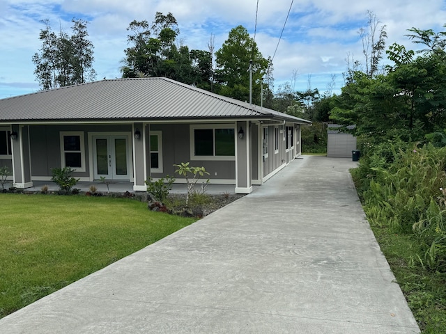 15-2797 Lai St, Pahoa, HI 96778 - view of front of home featuring a front lawn, board and batten siding, metal roof, driveway, and french doors