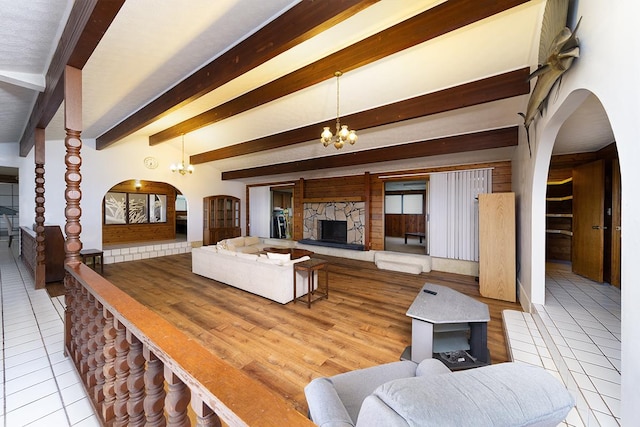 1890 Kaiao St, Hilo, HI 96720 - living room with arched walkways, a chandelier, tile patterned floors, a stone fireplace, and beam ceiling