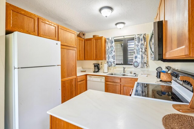 4460 Nehe Rd Unit 116, Lihue, HI 96766 - kitchen with white appliances, a sink, light countertops, a textured ceiling, and a peninsula