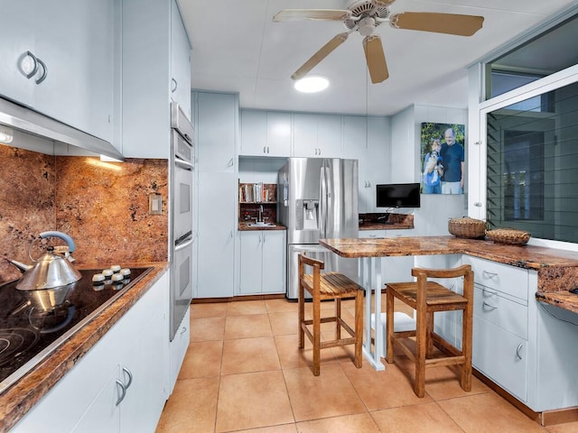 224 Paukaa Dr, Hilo, HI 96720 - kitchen with stainless steel refrigerator with ice dispenser, black electric cooktop, ceiling fan, backsplash, and white cabinets