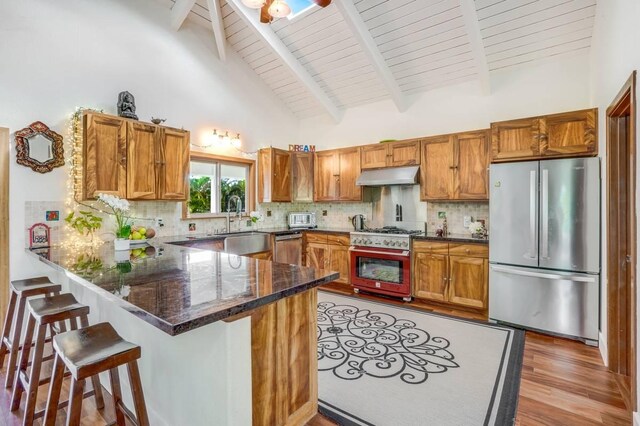 5750-M Olohena Rd, Kapaa, HI 96746 - kitchen with appliances with stainless steel finishes, under cabinet range hood, a peninsula, light wood-style flooring, and brown cabinetry
