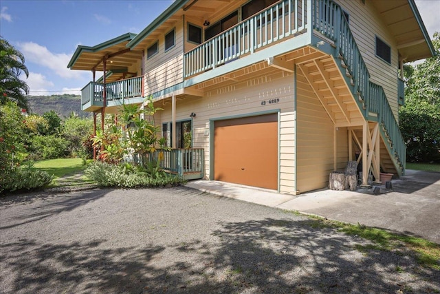 82-6289 Kahauloa St, Captain Cook, HI 96704 - view of property exterior featuring a balcony, an attached garage, stairs, and asphalt driveway