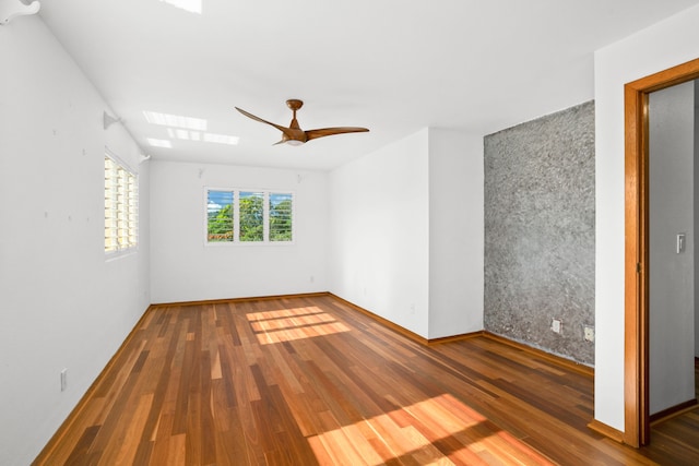 4879 Lani Rd, Kapaa, HI 96746 - empty room with a skylight, wood finished floors, ceiling fan, an accent wall, and baseboards