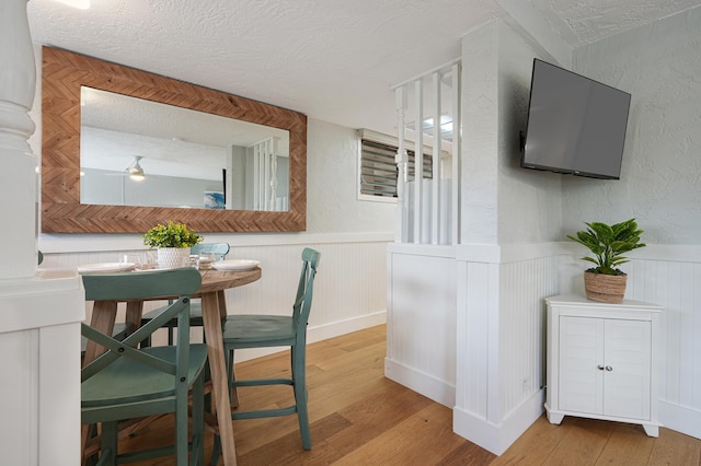 5061 Lawai Rd Unit 323, Koloa, HI 96756 - dining space featuring a textured ceiling, light wood finished floors, and wainscoting