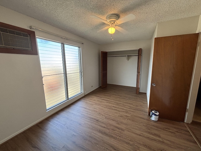 33 Hualalai St Unit 203, Hilo, HI 96720 - unfurnished bedroom with wood finished floors, a textured ceiling, a closet, ceiling fan, and a wall mounted AC