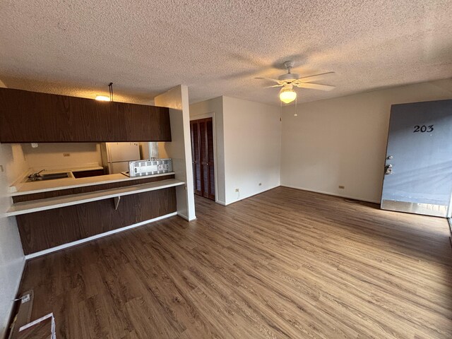 33 Hualalai St Unit 203, Hilo, HI 96720 - kitchen with wood finished floors, a ceiling fan, a textured ceiling, dark brown cabinets, and light countertops