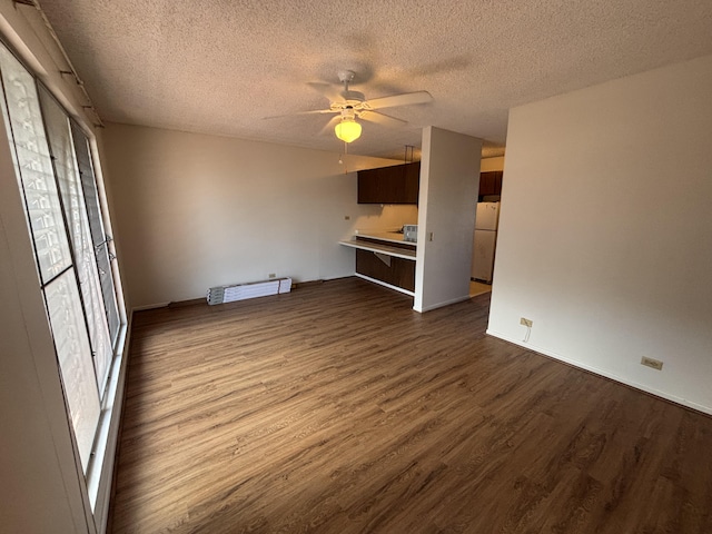 33 Hualalai St Unit 203, Hilo, HI 96720 - unfurnished living room with dark wood-type flooring, a textured ceiling, ceiling fan, baseboards, and a baseboard radiator