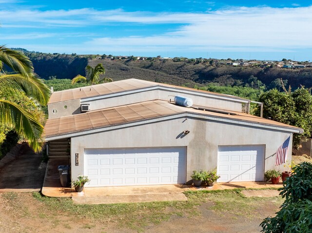 3719 Uwao St, Hanapepe, HI 96716 - view of front of property with a detached garage, stucco siding, and dirt driveway