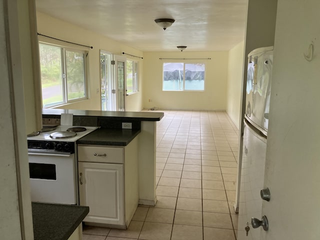 14-760 Seaview Rd, Pahoa, HI 96778 - kitchen featuring white range with electric stovetop, light tile patterned floors, dark countertops, white cabinetry, and freestanding refrigerator
