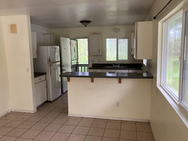 14-760 Seaview Rd, Pahoa, HI 96778 - kitchen featuring freestanding refrigerator, a sink, a peninsula, dark countertops, and a kitchen breakfast bar