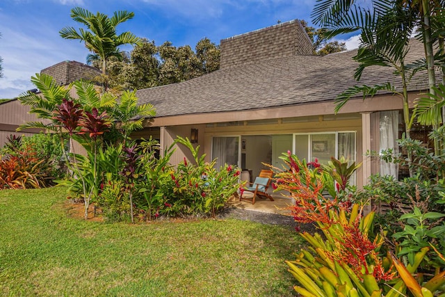 5280 Ka Haku Rd Unit 8, Princeville, HI 96722 - rear view of house with a shingled roof, a lawn, a chimney, and a patio