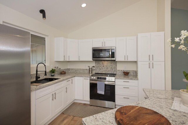 15-1042 Amau Rd, Keaau, HI 96749 - kitchen with stainless steel appliances, a sink, lofted ceiling, white cabinetry, and tasteful backsplash