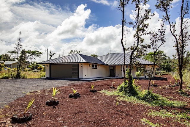 15-1042 Amau Rd, Keaau, HI 96749 - ranch-style house with a standing seam roof, an attached garage, metal roof, dirt driveway, and board and batten siding