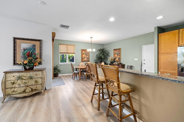69-555 Waikoloa Beach Dr Unit 2605, Waikoloa, HI 96738 - kitchen with light wood-style flooring, a chandelier, baseboards, fridge, and a breakfast bar