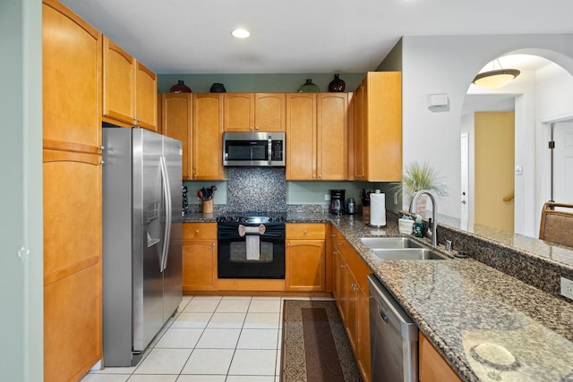 69-555 Waikoloa Beach Dr Unit 2605, Waikoloa, HI 96738 - kitchen with appliances with stainless steel finishes, a sink, dark stone countertops, light tile patterned flooring, and arched walkways