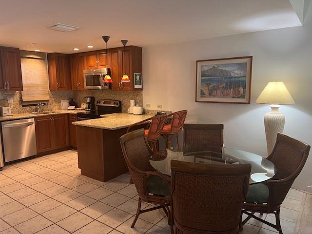 75-6040 Royal Sea Cliff Clb Unit 102, Kailua-Kona, HI 96740 - kitchen featuring stainless steel appliances, a peninsula, a sink, decorative backsplash, and light tile patterned flooring