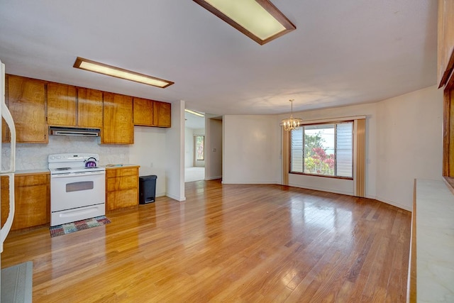 17-549 Ipuaiwaha St, Keaau, HI 96749 - kitchen featuring white range with electric cooktop, ventilation hood, brown cabinets, a chandelier, and healthy amount of natural light