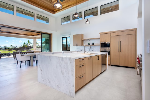 68-1049 Ke Kailani Dr, Kamuela, HI 96743 - kitchen featuring modern cabinets, a sink, a towering ceiling, light stone counters, and light brown cabinetry