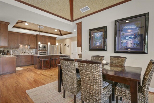 68-1122 Kaniku Dr Unit 111, Kamuela, HI 96743 - dining area with light wood finished floors, a tray ceiling, and ornamental molding