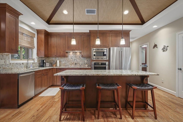 68-1122 Kaniku Dr Unit 111, Kamuela, HI 96743 - kitchen with stainless steel appliances, a sink, a tray ceiling, light wood-style floors, and backsplash