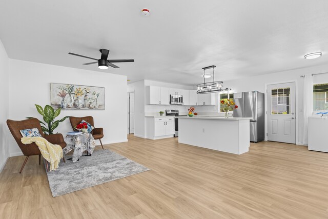 15-385 Puni Makai Loop, Pahoa, HI 96778 - living area featuring washer / dryer, light wood-type flooring, a ceiling fan, a chandelier, and baseboards