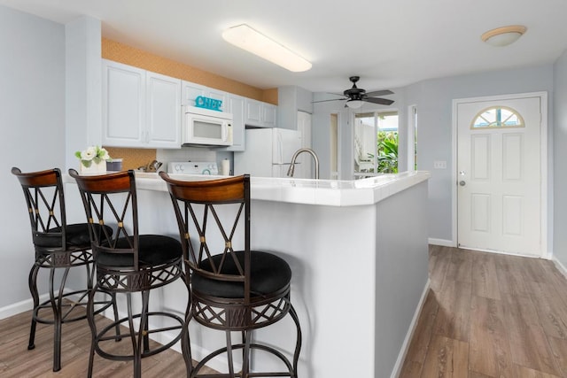 75-6081 Alii Dr Unit V101, Kailua-Kona, HI 96740 - kitchen with white appliances, a breakfast bar, baseboards, and light wood finished floors
