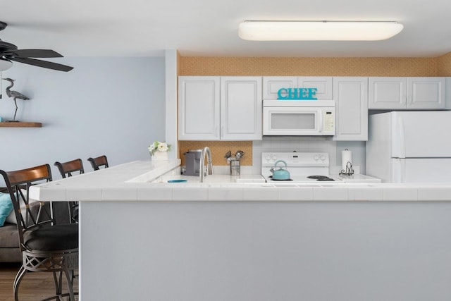 75-6081 Alii Dr Unit V101, Kailua-Kona, HI 96740 - kitchen featuring white appliances, tile countertops, a kitchen breakfast bar, and white cabinets