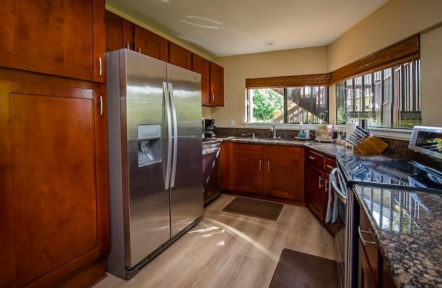 3920 Wyllie Rd Unit 9A, Princeville, HI 96722 - kitchen featuring appliances with stainless steel finishes, dark stone countertops, a sink, and light wood-style flooring